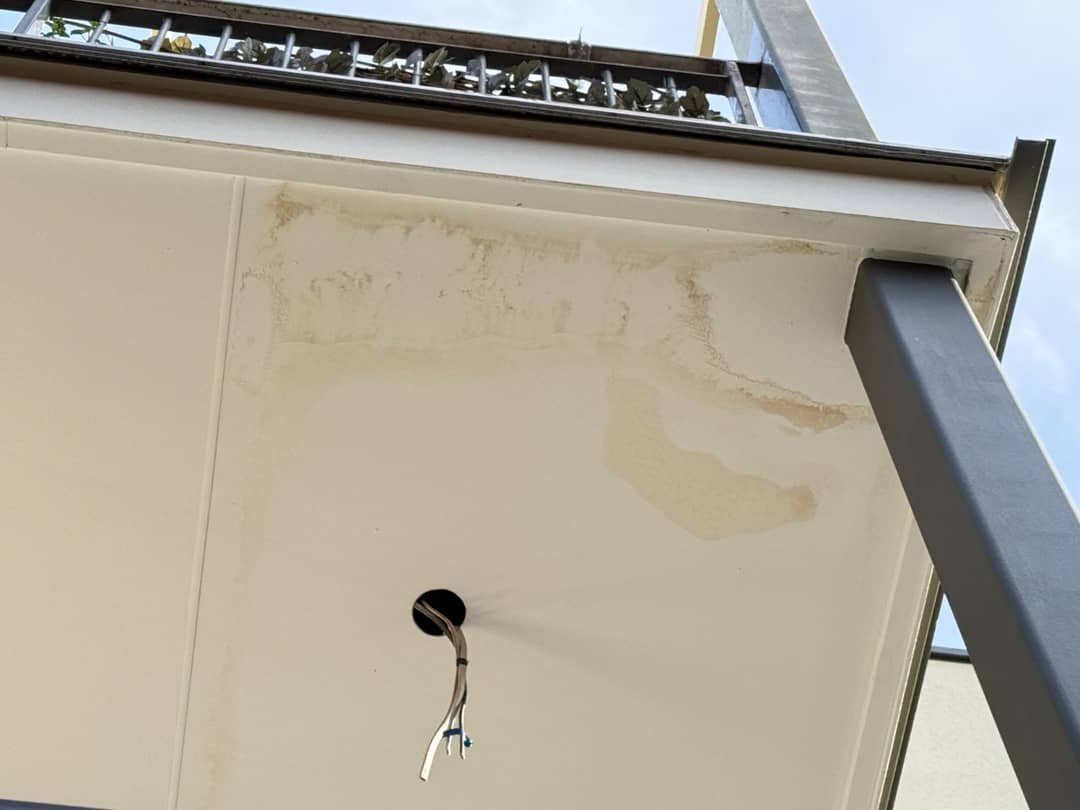 Water damage and staining on a ceiling below a balcony, with the source further away than it appears