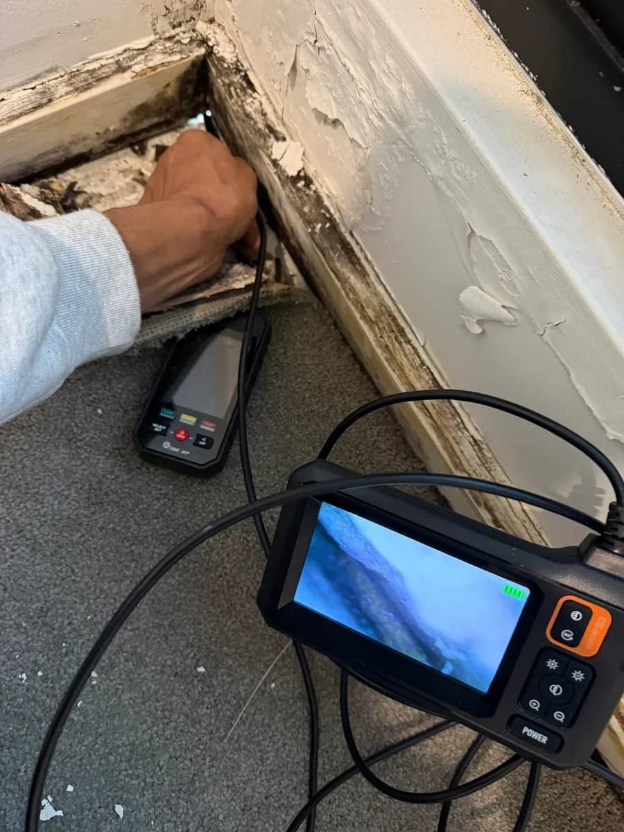 Cavity inspection camera probe being fed into a crack to look inside a concealed wall void