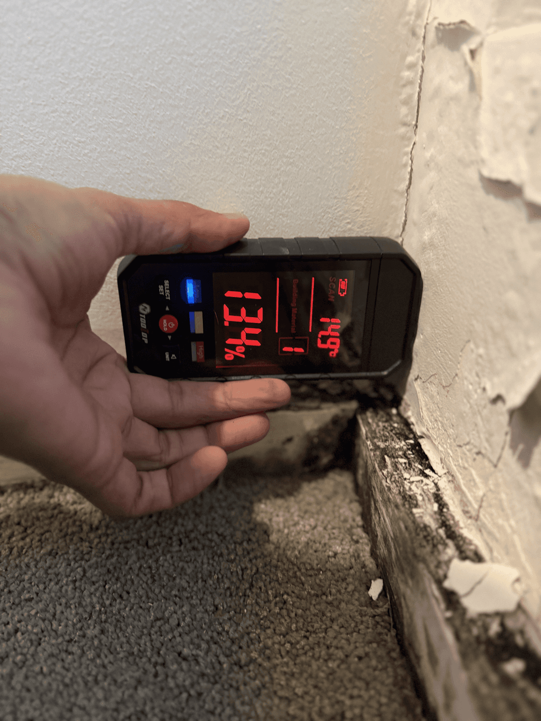 Moisture meter and leak detection equipment being used on a bathroom floor to trace a shower leak to its source