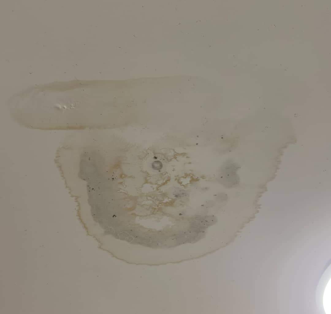 Water-damaged ceiling in an apartment showing staining and peeling paint from a leak in a strata building