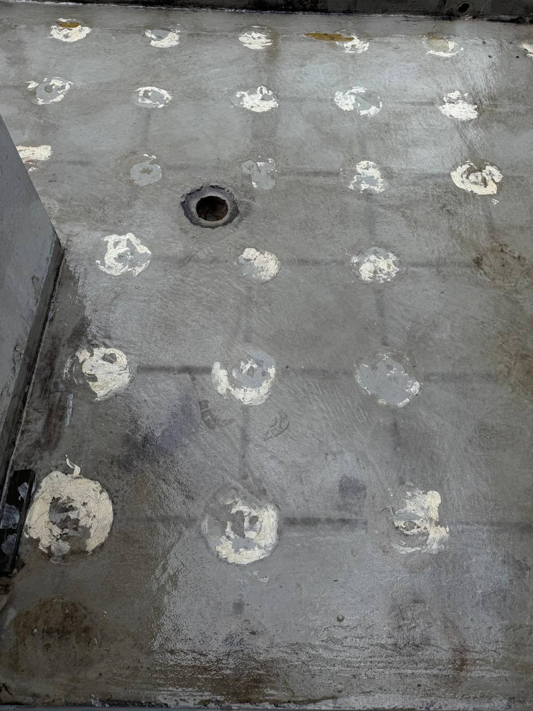 Close-up of a rooftop membrane showing degraded grid lines matching the paver joints above.