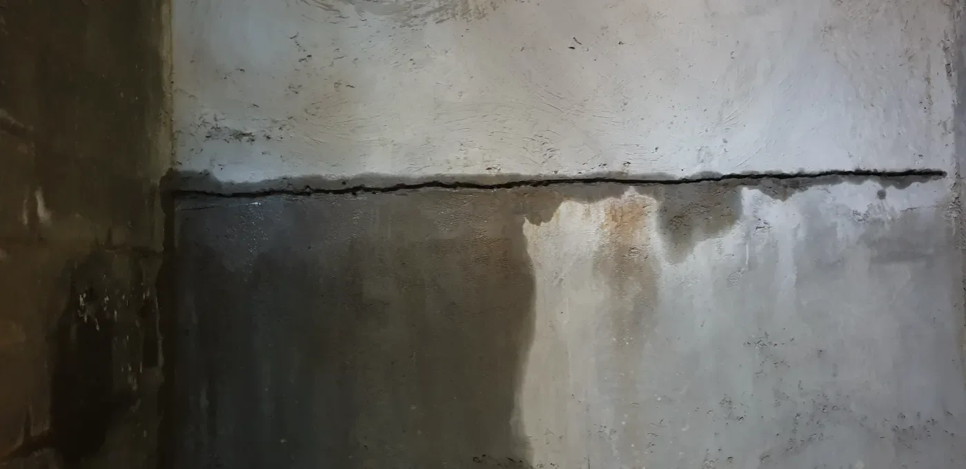 Horizontal crack in the basement wall with a visible water line