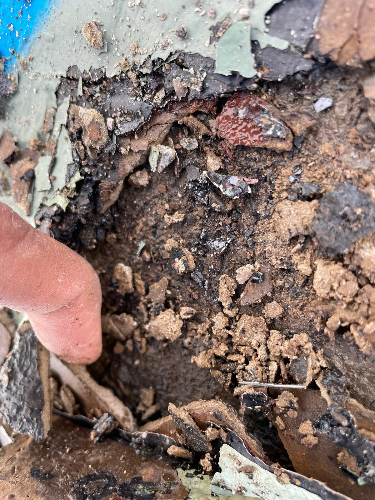 Excavated section of roof revealing bitumen and debris between layers