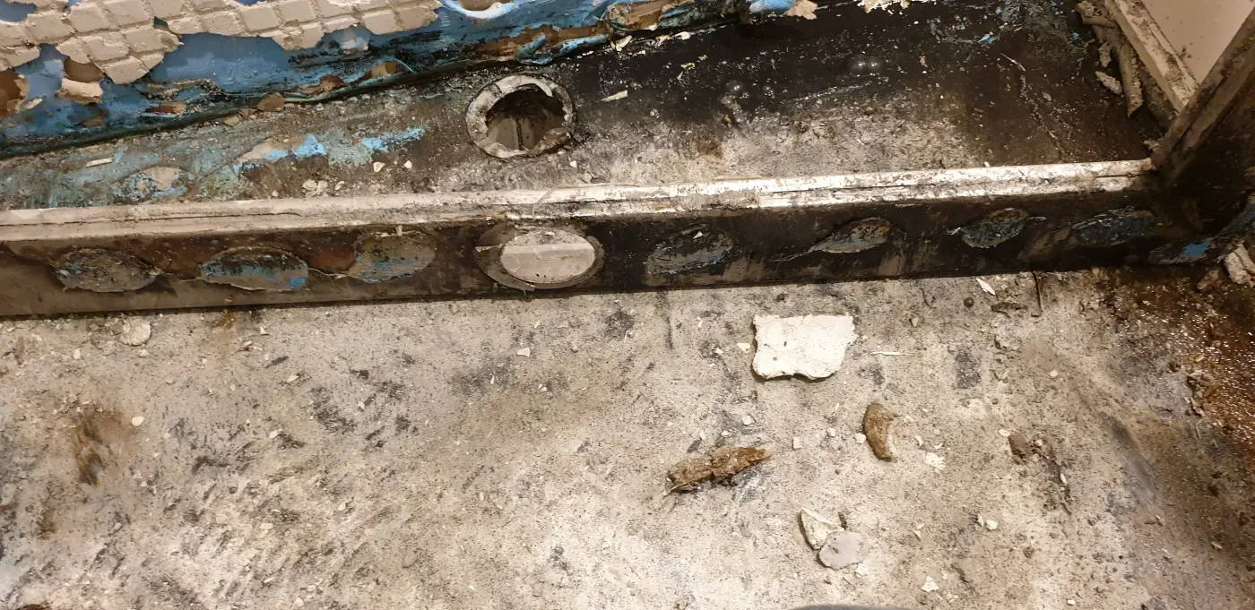 The threshold and pipe penetrations after removal of the floor finish