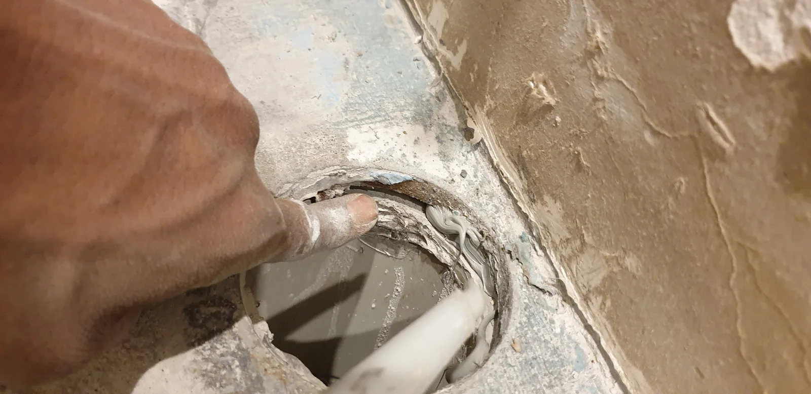 Waterproofing being applied by hand around a floor penetration