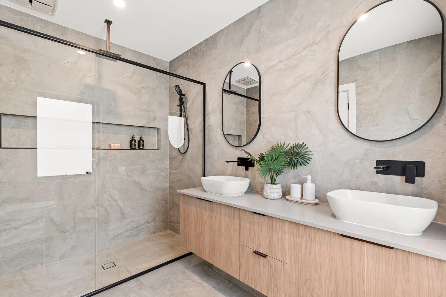 Finished bathroom with a tiled walk-in shower, glass screen and double vanity